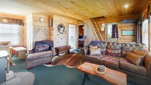 L’intérieur d’un chalet confortable, avec un plafond en bois, un canapé en cuir, une table en bois et une cheminée.
