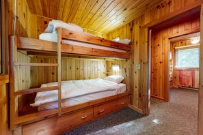 Habitación con literas, paredes de madera y suelo alfombrado.