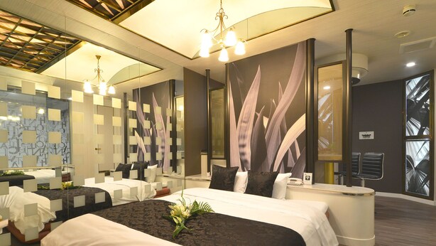 Una habitación de hotel moderna con una cama grande, una zona de estar y un mostrador de recepción.