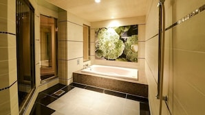 Un baño moderno con una bañera grande, cabina de ducha con mampara de vidrio y un mural decorativo en la pared.