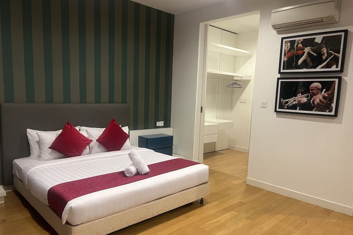 A hotel room with a bed, a wardrobe, a mirror, and a picture on the wall.