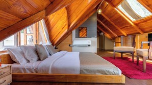 Een slaapkamer met een houten plafond, een bed, een stoel en een rood tapijt.
