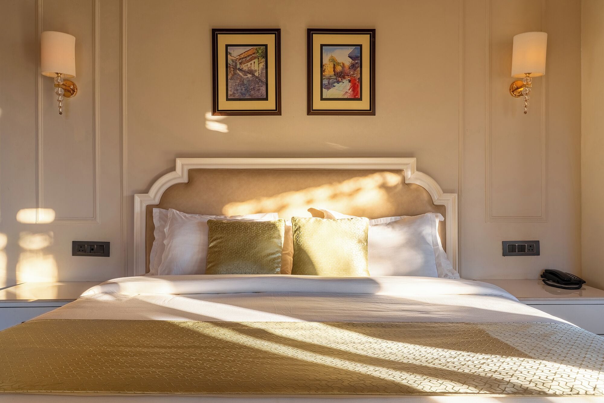 Una camera da letto ben illuminata con un letto grande, due opere d'arte incorniciate al muro e applique.