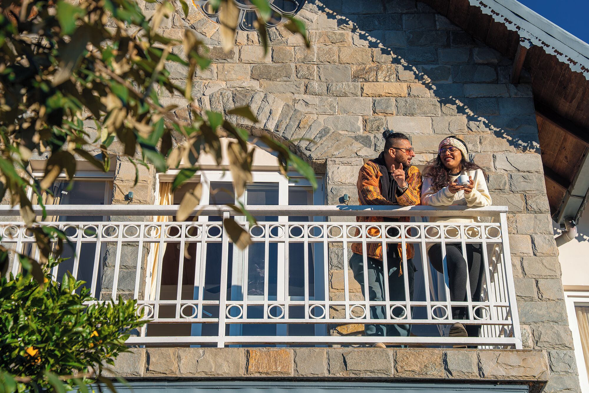 A stone building with a balcony featuring a white metal railing.