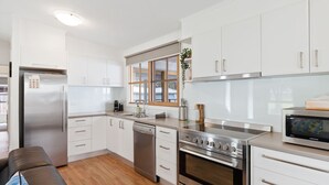 Una cocina moderna con armarios blancos, electrodomésticos de acero inoxidable y piso de madera.