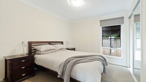 Un dormitorio con cama, mesitas de noche y ventana con vistas a la vegetación.