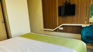 A hotel room with a bed, a television mounted on the wall, and a desk with a chair. - Hotel Global Inn (Amritsar)
