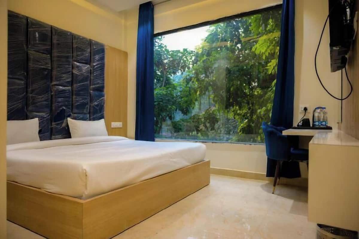 A bedroom with a large bed, a desk, and a window with a view of trees.