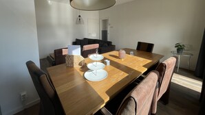 Ett modernt matområde med ett träbord, bruna läderstolar, en hängande lampa och en liten krukväxt.