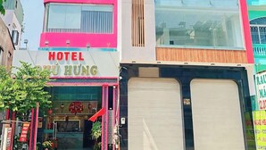 Een meerhoog hotel met een opvallende roze gevel, grote ramen en een duidelijke ingang met een bord waarop 