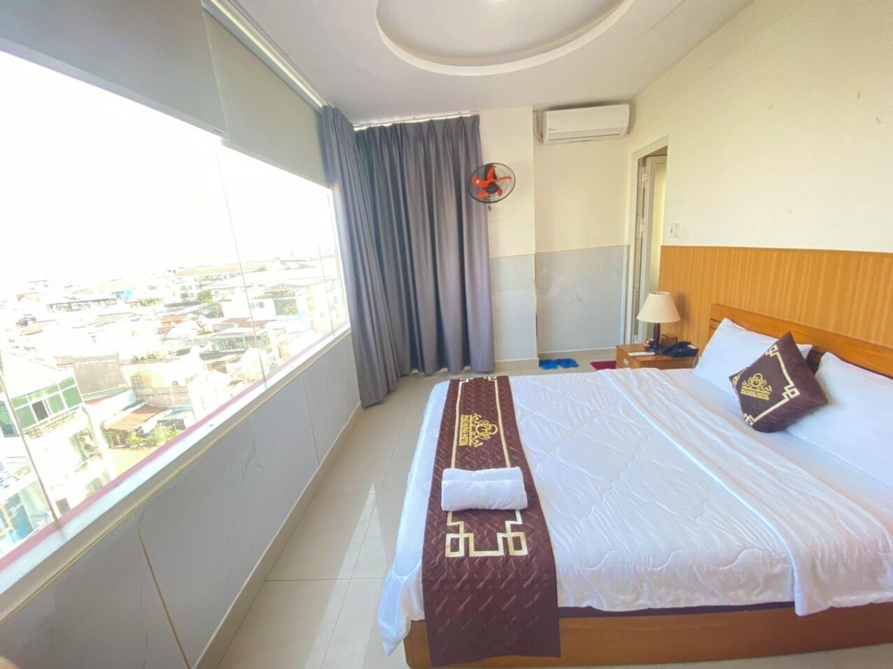 Een hotelkamer met een groot bed, uitzicht op de stad en een plafondventilator.