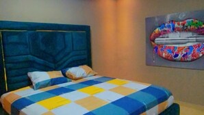 A bedroom with a bed, a ceiling fan, and a wall-mounted artwork. - Magic City Apartment (Kasoa)
