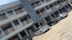 A multi-story building with a parking area. - Magic City Apartment (Kasoa)