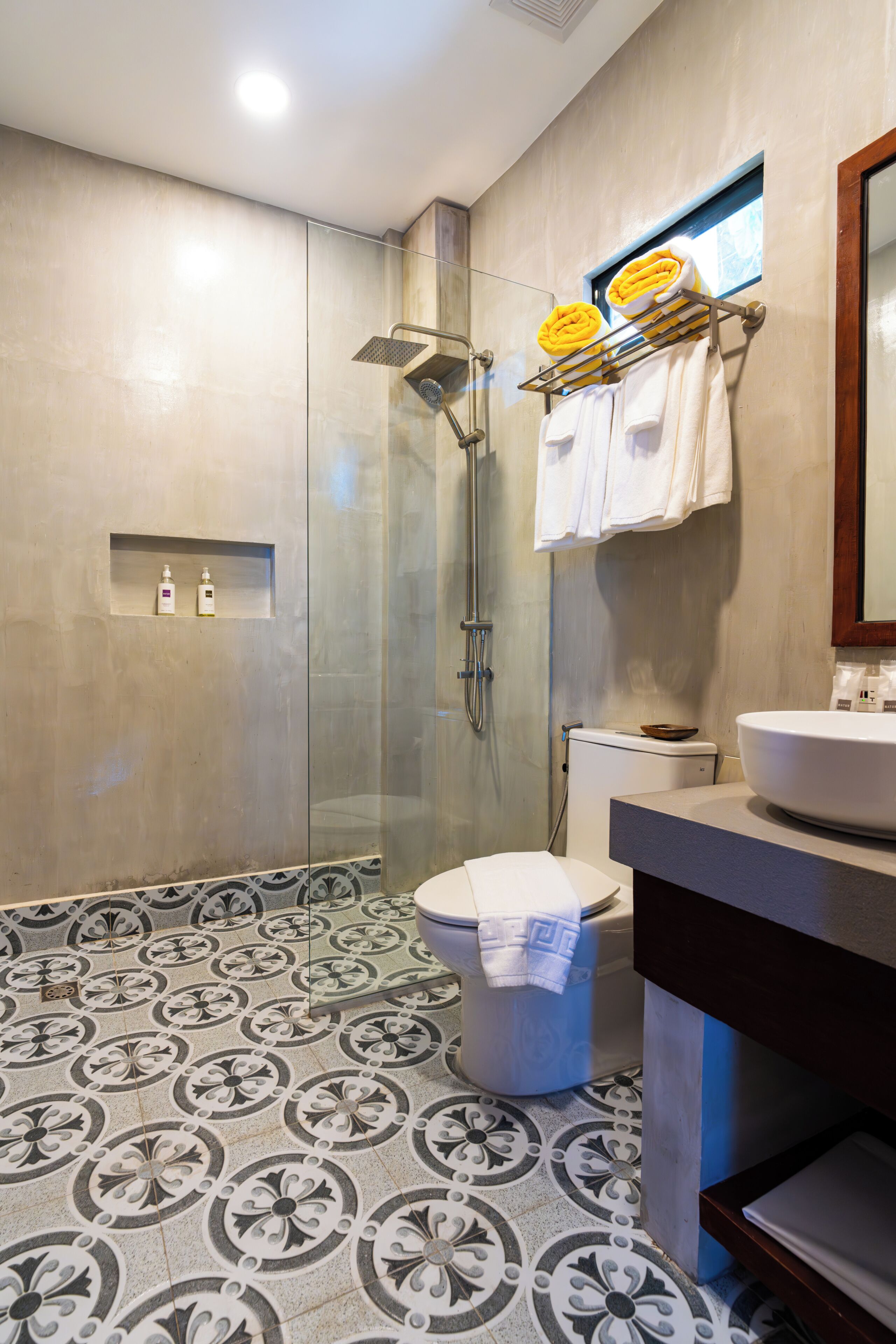 A modern bathroom with a glass shower enclosure, a toilet, and a sink with a mirror.