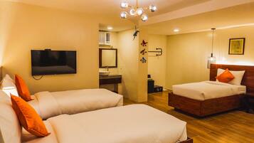 A hotel room with two beds, a TV, a mirror, a sink, and a ceiling light fixture.