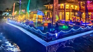 Un hotel frente al agua con piscina, bar y zona de comedor.