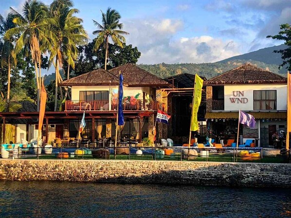 A waterfront hotel with multiple buildings, outdoor seating, and flags.