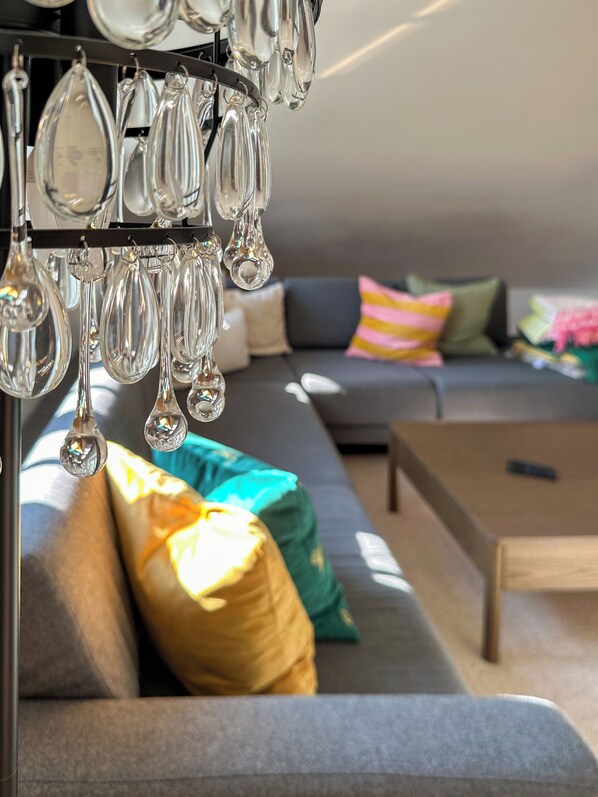 A modern living room with a gray sofa, colorful cushions, and a hanging light fixture.