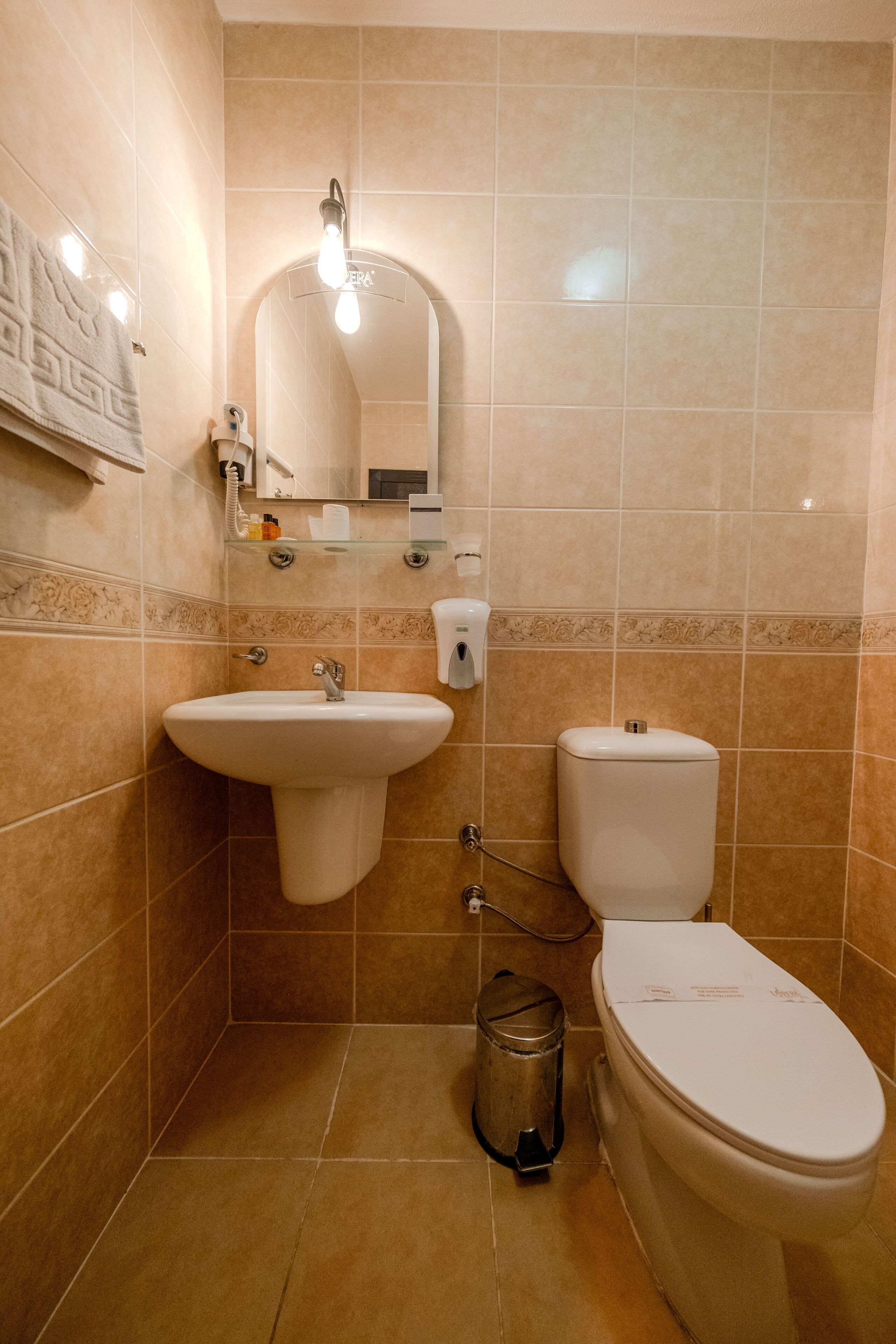 Un baño con lavamanos, inodoro y cubo de basura.