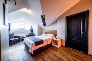 Un dormitorio con cama, mesita de noche, una silla y una puerta.