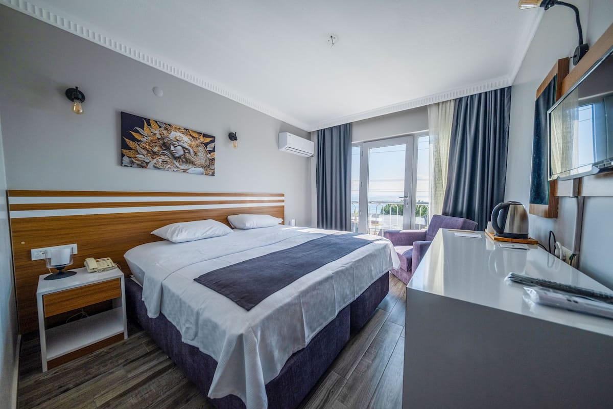 Quarto de hotel com uma cama grande, uma escrivaninha, uma cadeira, máquina de café e vista para o exterior.