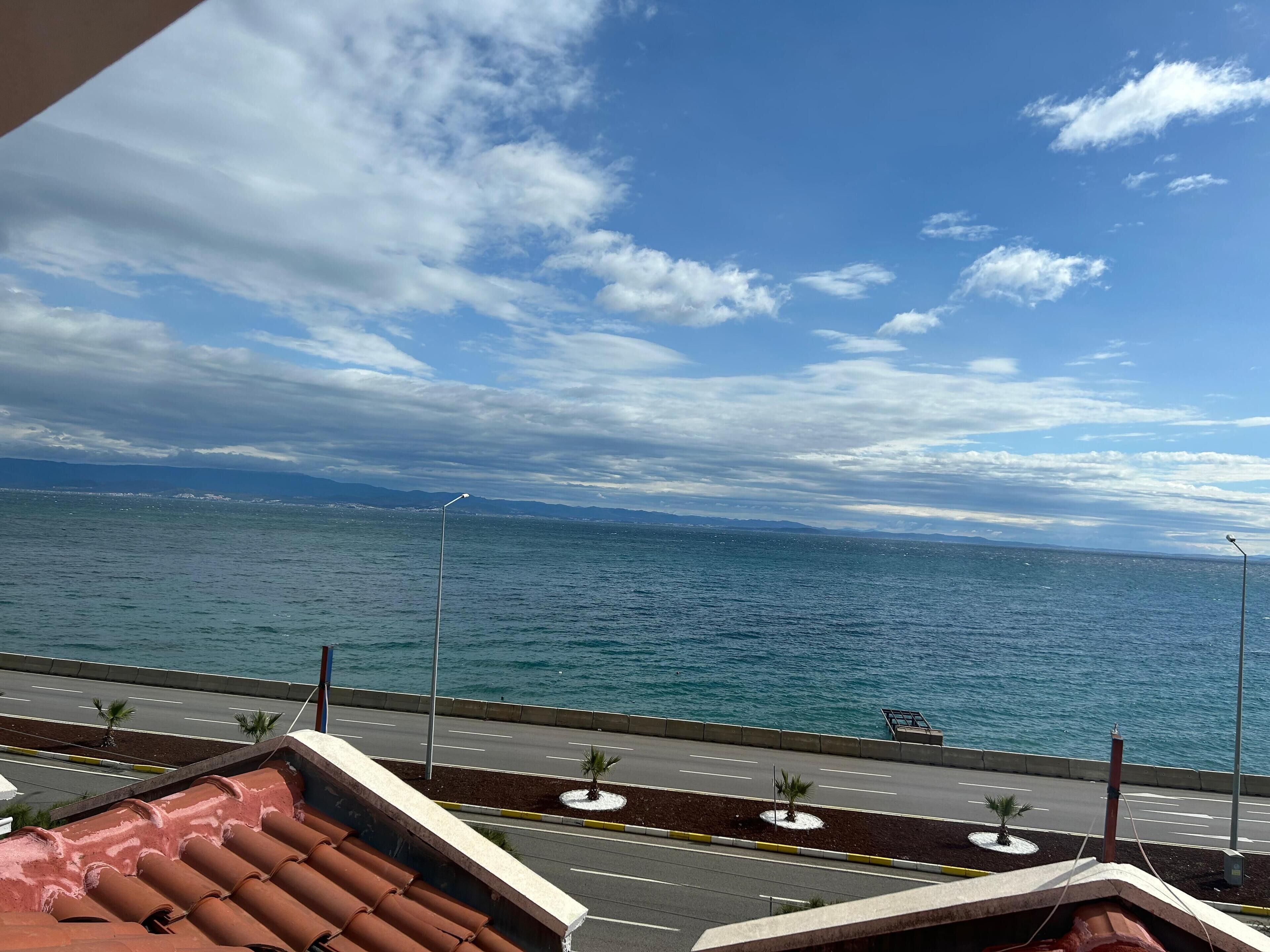Una carretera costera con vistas despejadas al mar y montañas a lo lejos.