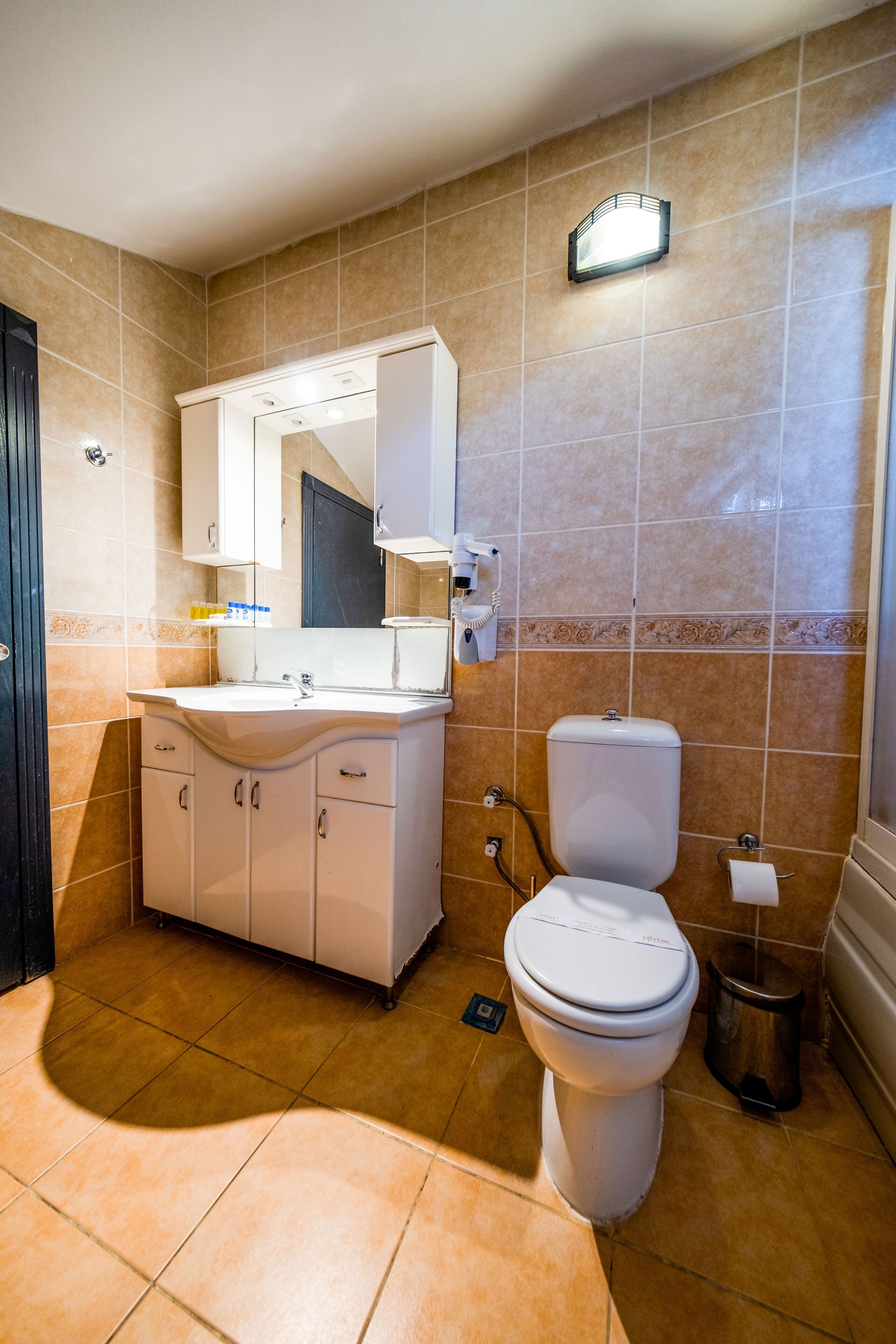 A bathroom with a white sink, mirror, and toilet.
