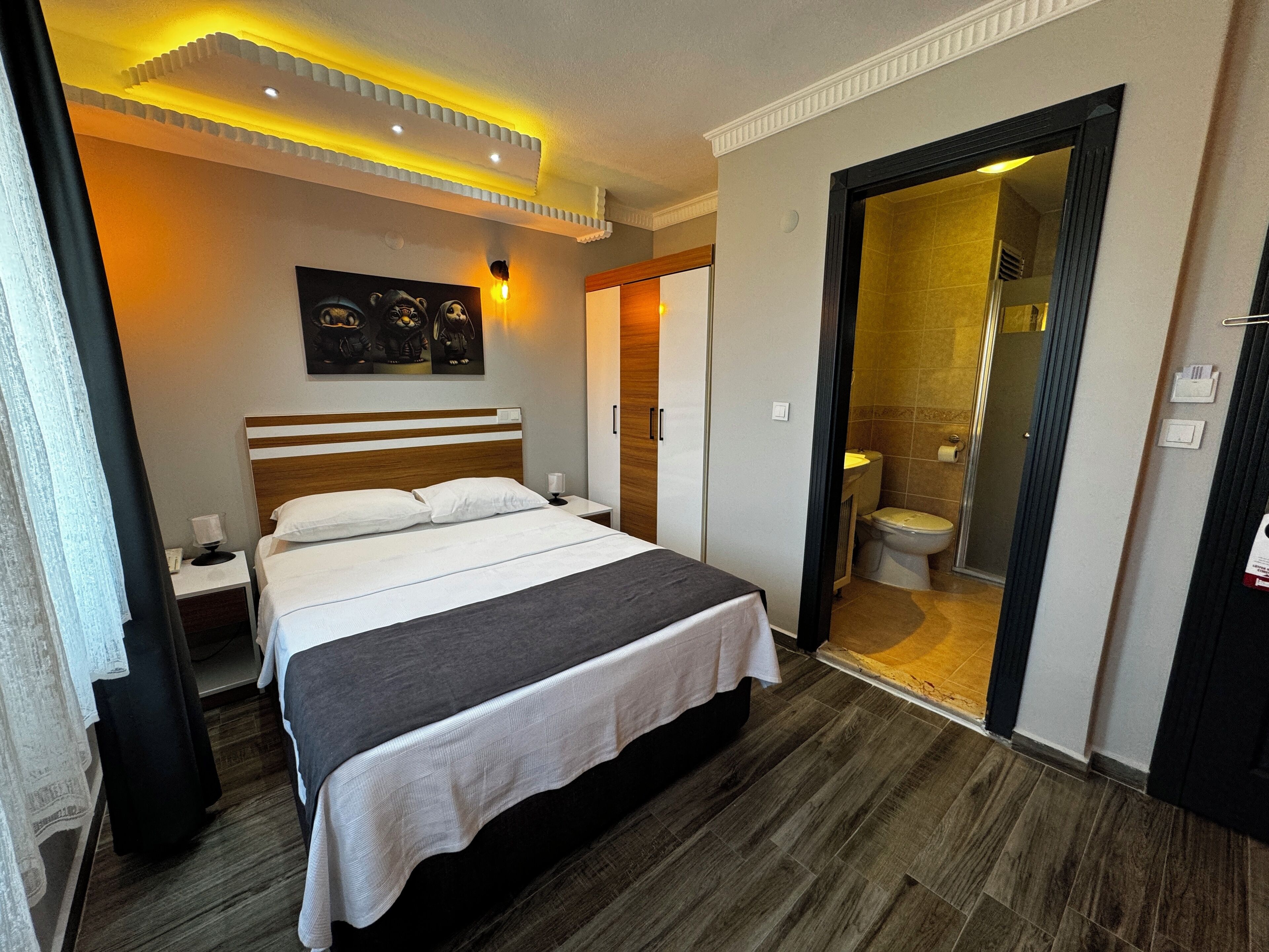 A hotel room with a large bed, a nightstand, a wall-mounted light, and a door leading to a bathroom.