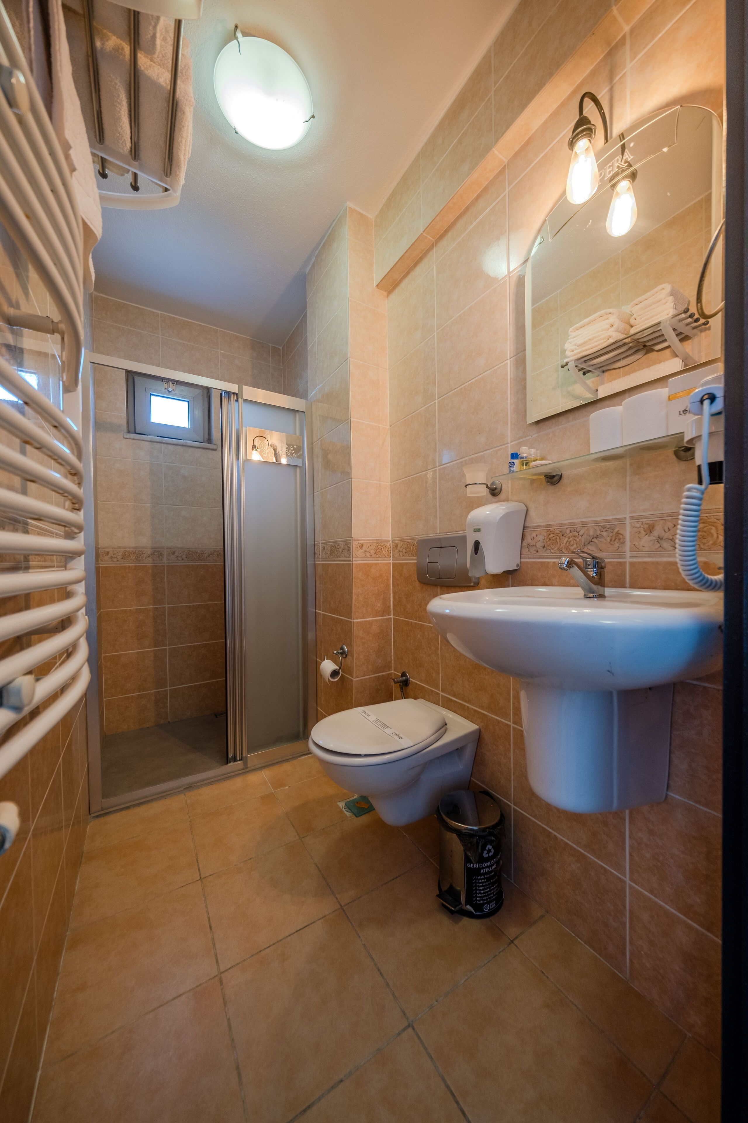 Un baño con ducha, inodoro, lavabo y toallero.