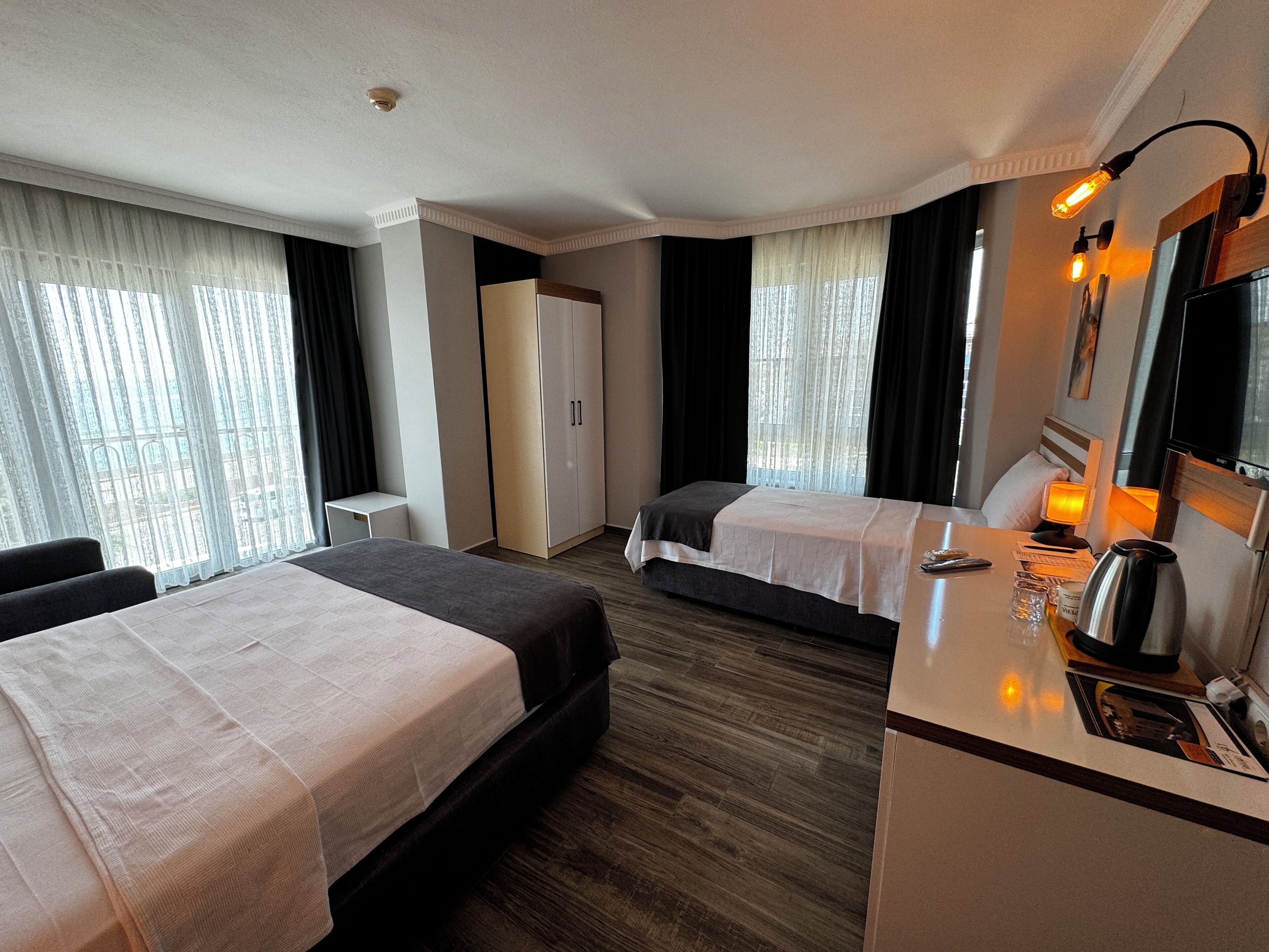 A hotel room with two beds, a desk with a lamp, a coffee maker, and a TV.