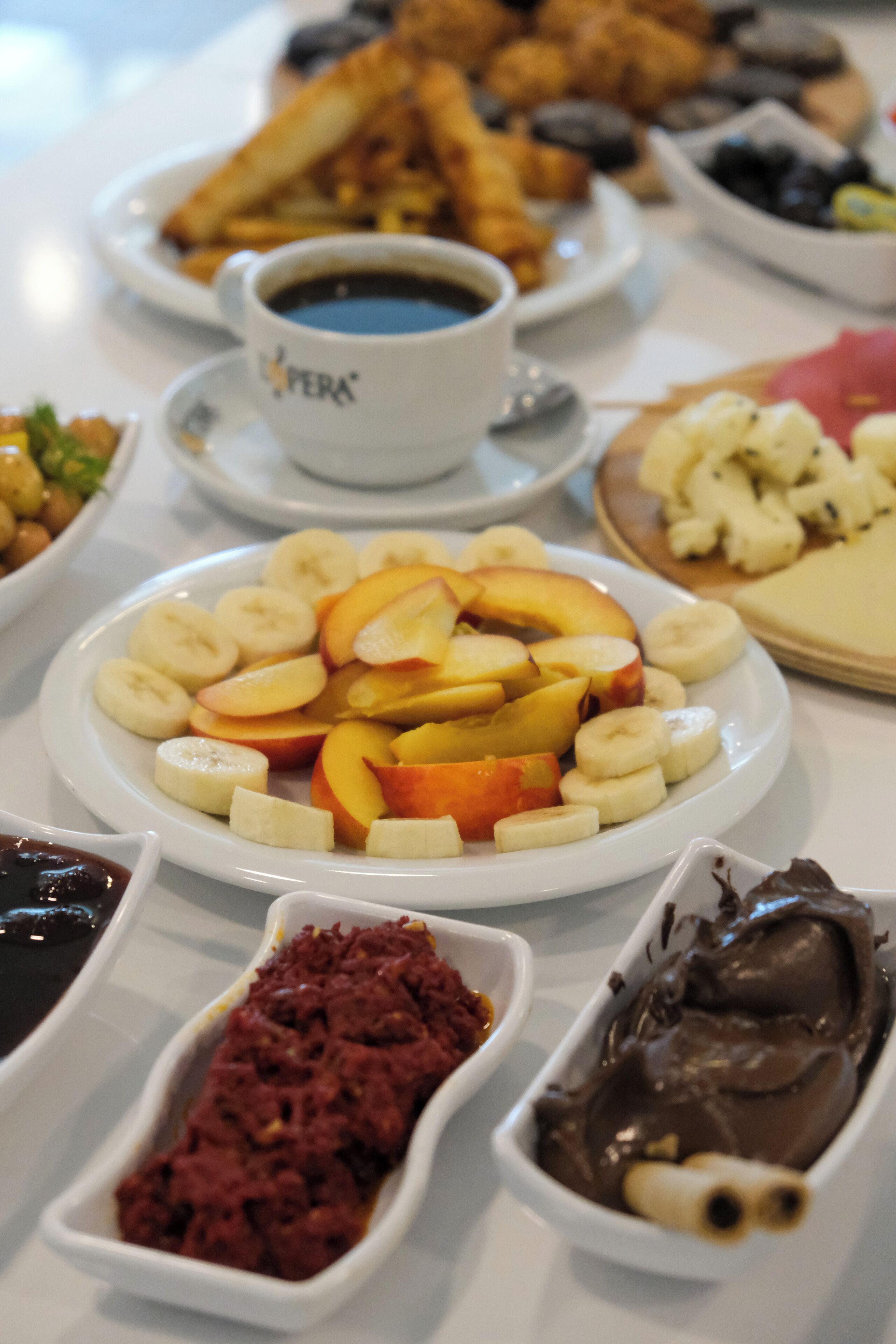 Una mesa con diversas opciones de comida, incluyendo plátanos en rodajas, manzanas y chocolate.