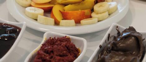 Una mesa con diversas opciones de comida, incluyendo plátanos en rodajas, manzanas y chocolate.