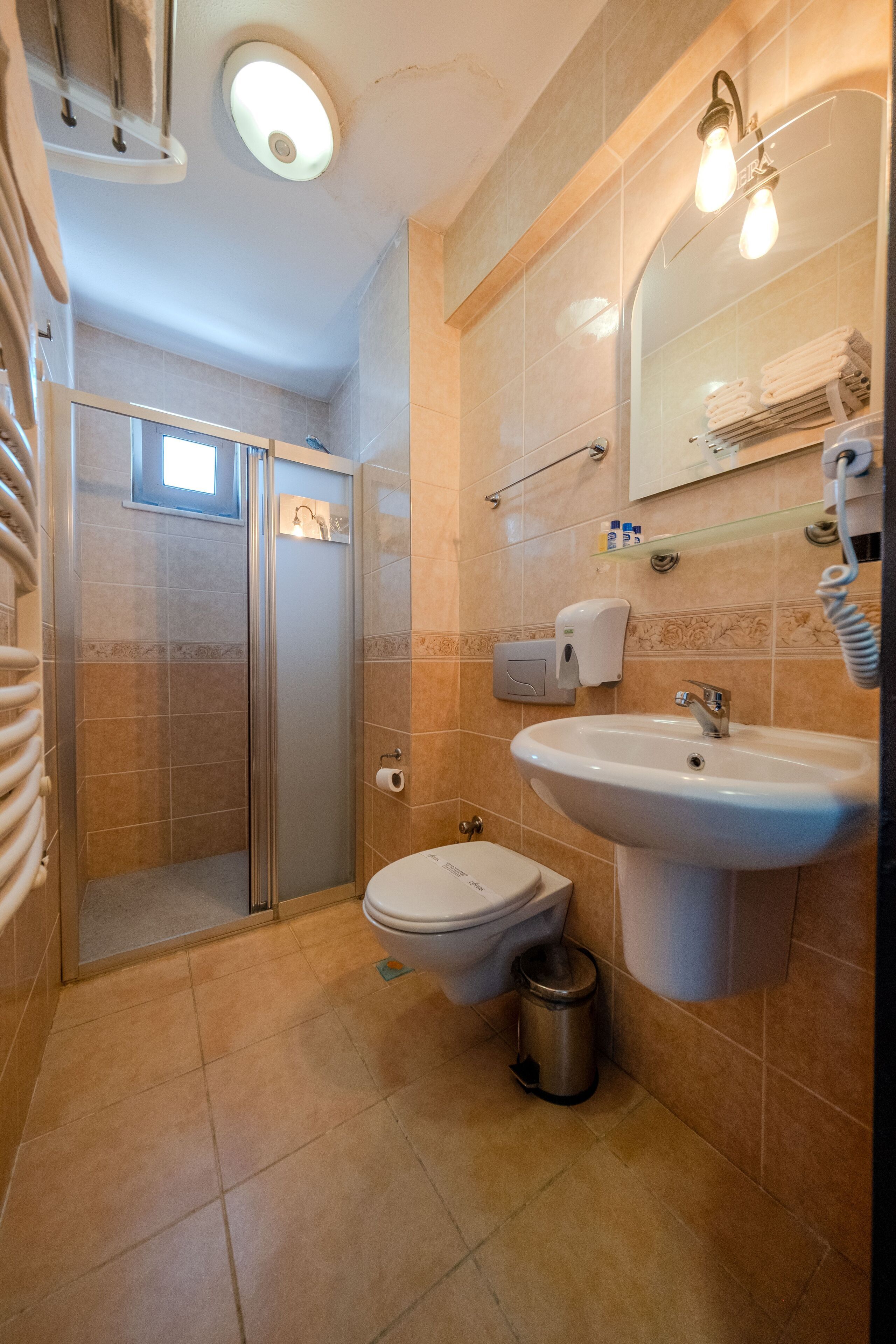 Une salle de bain équipée d’une douche, de toilettes, d’un lavabo et d’un miroir avec éclairage.