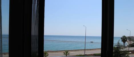 A view from a window overlooking a coastal road with a clear sky.