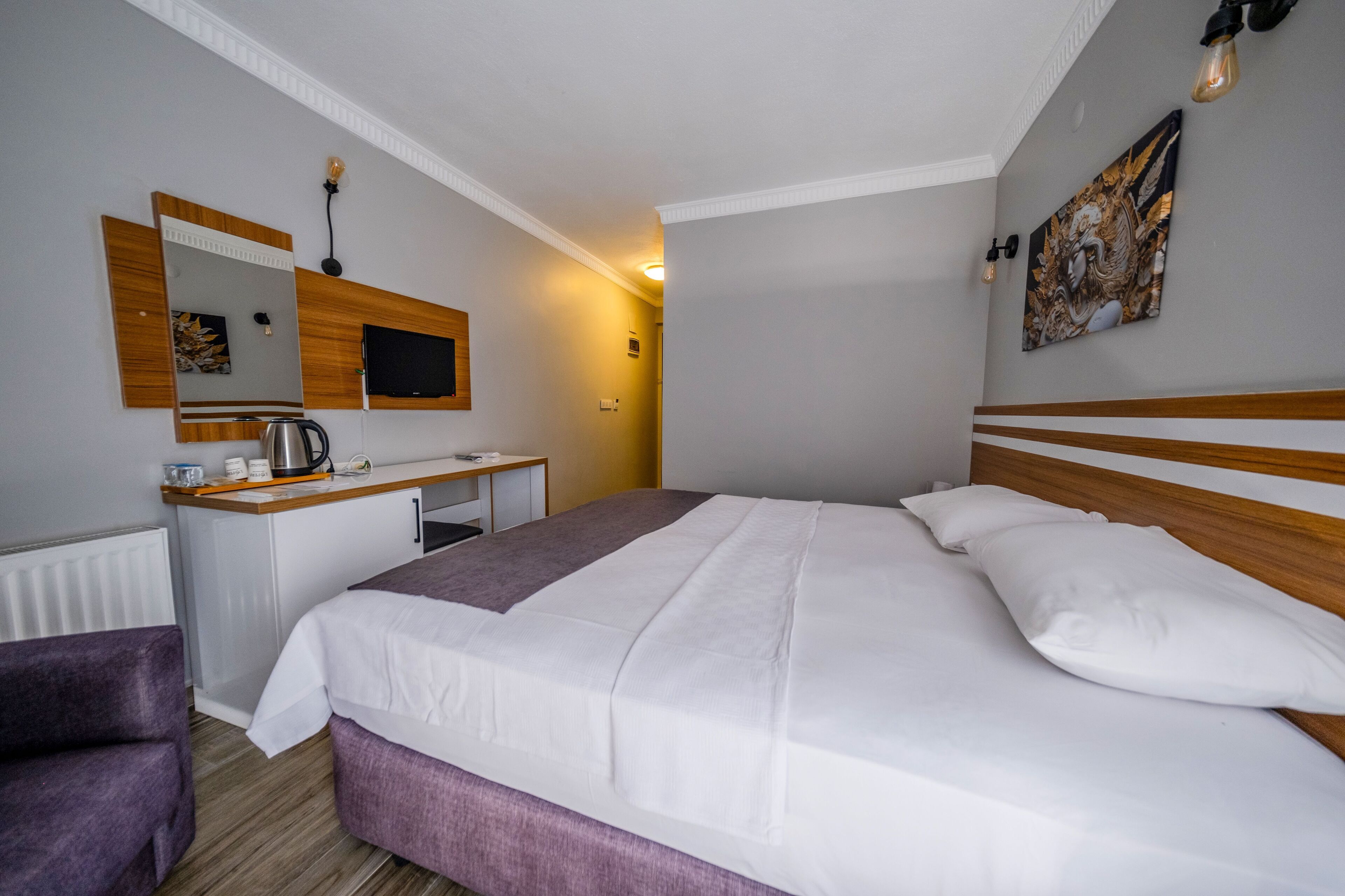 Une chambre d’hôtel avec un lit, un bureau et une chaise, une télévision et un tableau au mur.