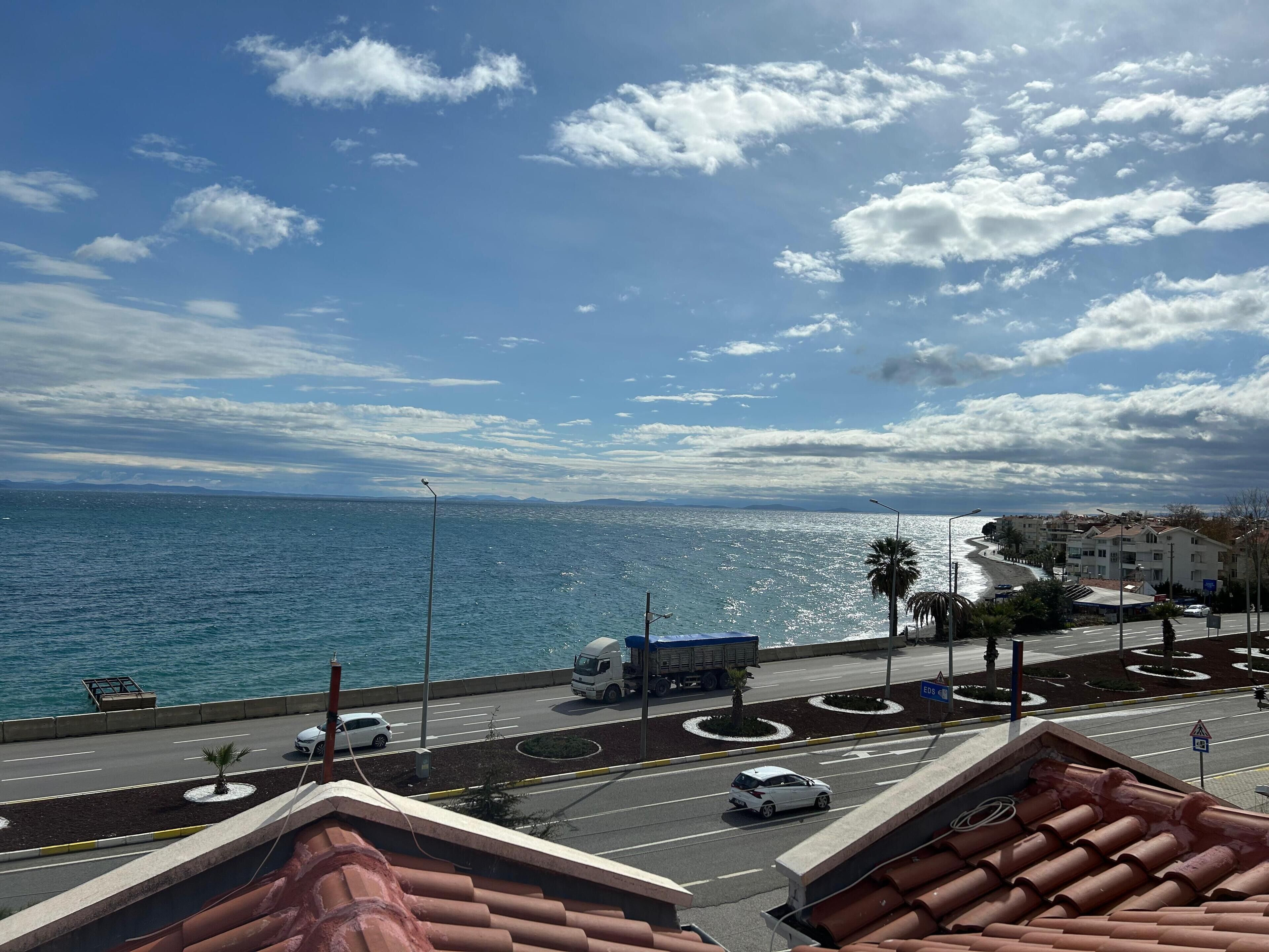 A coastal road with a view of the sea and distant mountains.