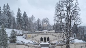 A snow-covered fountain with statues, a garden, and a building in the background. - Villa Alpenpanorama (Ohlstadt)