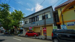 A street view with a building that has multiple signs, including one for a hotel named "APOTEK Bella Lha". - OYO 93682 Blessing's Kediri Homestay Syariah (Kediri)