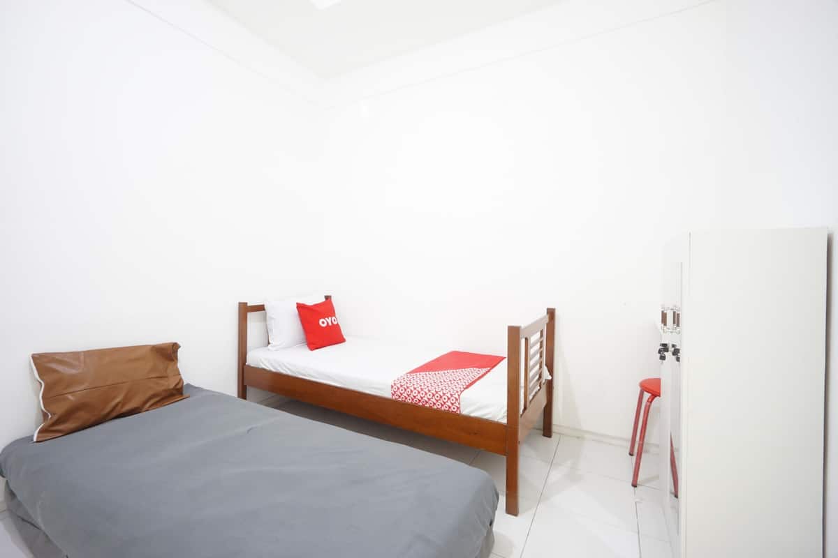 Ein Schlafzimmer mit einem Bett, einem hölzernen Kopfseitenverkleidung, einem roten Hocker und einem weißen Kleiderschrank.