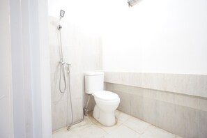 Bathroom features a shower unit and toilet, with a doorway leading to a larger room.