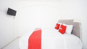 A room with a bed, a TV mounted on the wall, and a red and white bedspread. - OYO 93682 Blessing's Kediri Homestay Syariah (Kediri)