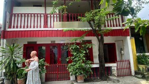A two-story building with a red and white facade, a balcony with red railings, and a gated entrance. - SPOT ON 93681 Qodri Homestay Syariah (Surabaya)