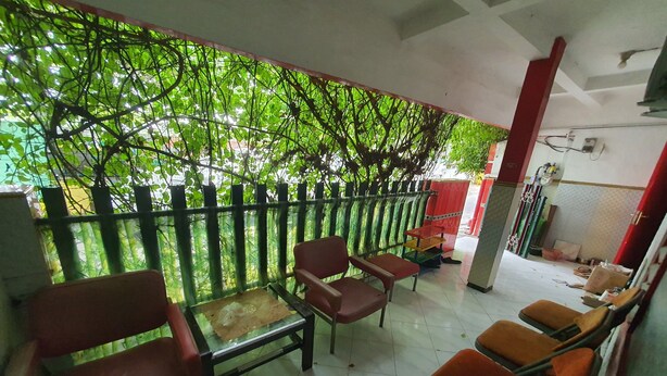 A room with a glass partition, several chairs, a table, and a view of greenery through the partition. - SPOT ON 93681 Qodri Homestay Syariah (Surabaya)