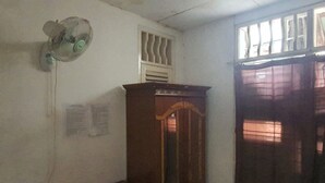 A room with a wooden cabinet, a wall-mounted fan, and a window with bars. - SPOT ON 93681 Qodri Homestay Syariah (Surabaya)