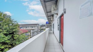 A narrow corridor with a tiled floor, a white wall, and a red door. - Hotel O Kost Naura (Somba Opu)