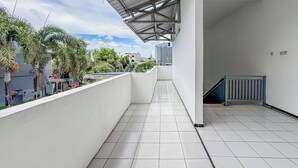 A clean, modern balcony with white tiled flooring and a metal roof structure. - Hotel O Kost Naura (Somba Opu)