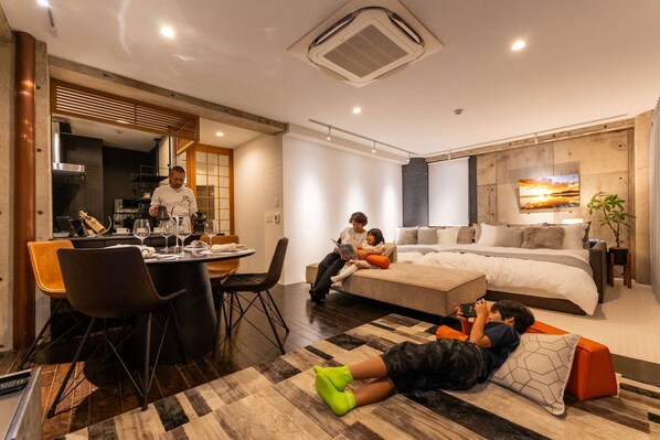 A modern hotel room with a dining area, a large bed, and a TV.