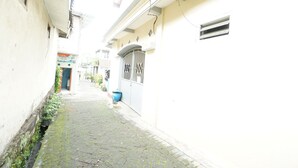 A narrow cobblestone alleyway between buildings with a metal gate and a blue trash bin.