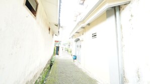 A narrow alleyway with buildings on either side, a blue trash bin, and a door at the end.