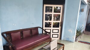A wooden sofa with a glass coffee table in front of a door with a decorative panel.